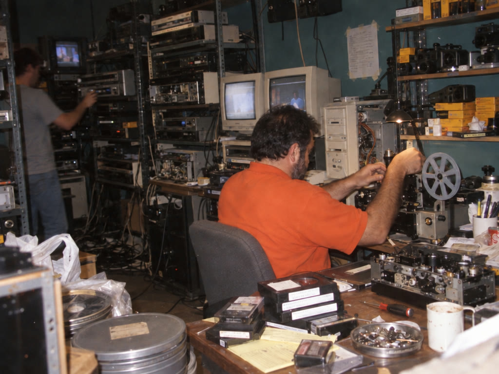 The Linof lab: racks of video decks, film reels and a projector, with the team at work